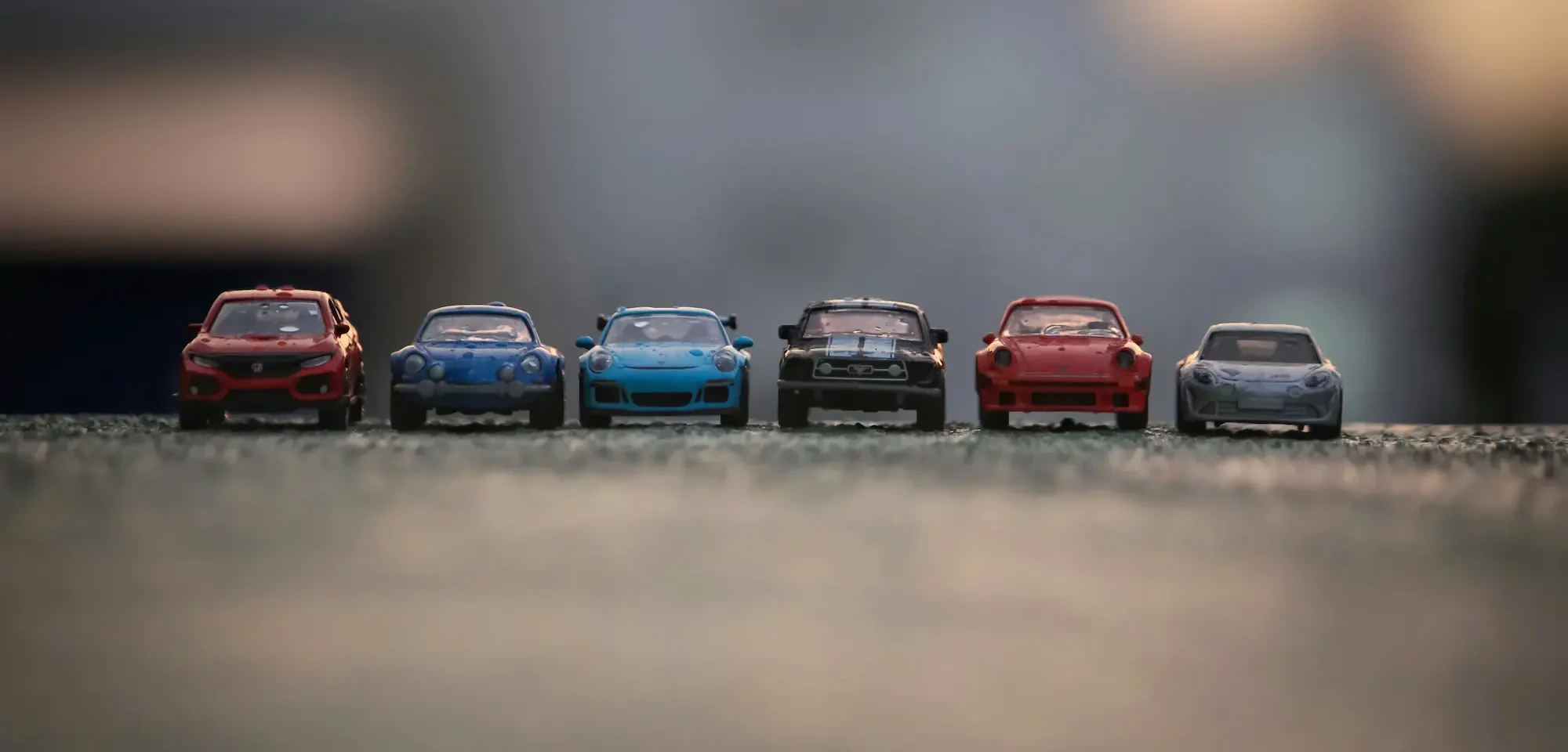 Colourful toy vehicles on rough concrete ground, with blurred foreground and background for focus.