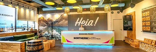 Interior of booking point with one staff member behind the counter, surrounded by a cozy lounge area and tour info.